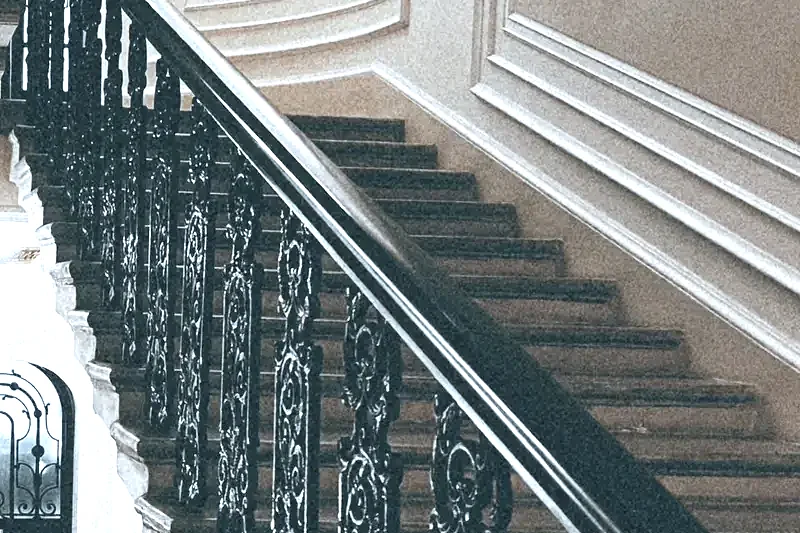 Escalier d’immeuble ancien : rampe en fer forgé, marches et murs moulurés entretenus
